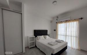 a white bedroom with a bed and a window at DUPLEX 3 in San Fernando del Valle de Catamarca