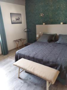 - une chambre avec un grand lit et un banc dans l'établissement La ferme du vincent, à Liergues