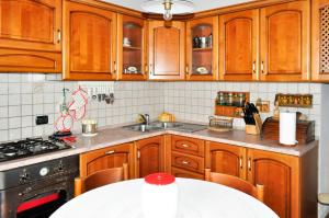 cocina con armarios de madera, fregadero y mesa en CASA VALENTINA, en Nocera Umbra