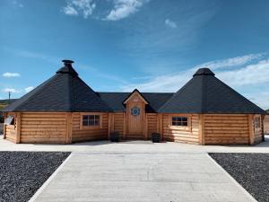 a large wooden cabin with a black roof at Ceide Glamping in Ballycastle