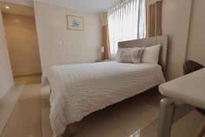 1 dormitorio con 1 cama con edredón blanco y ventana en Hotel Sandmelis, en Quito