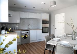 a kitchen with white cabinets and a table with chairs at Siegfried's Retreat in Grassington