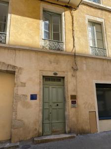 ein Gebäude mit einer grünen Tür und zwei Fenstern in der Unterkunft Nîmes Appartement de charme Terracotta in Nîmes