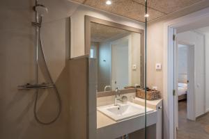 een badkamer met een douche, een wastafel en een spiegel bij Hostal Es Niu de Tamariu in Tamariu