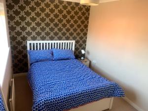 a bedroom with a bed with a blue comforter at The Hamptons in Shenley Lodge