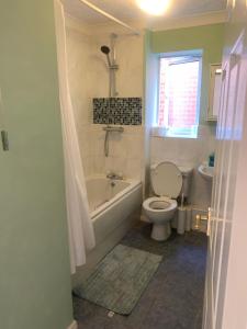 a bathroom with a toilet and a tub and a sink at The Hamptons in Shenley Lodge