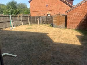 a backyard with a fence and a yard with a building at The Hamptons in Shenley Lodge