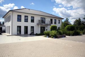 ein großes weißes Gebäude mit Balkon auf einem Parkplatz in der Unterkunft Hotel HeideZeiten in Walsrode