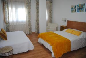 una habitación de hotel con 2 camas y una silla en Anduriña 2, en Monforte de Lemos