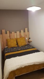 1 dormitorio con 1 cama con almohadas amarillas en Chez Mélissa, en Millau