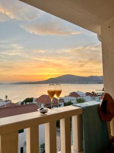 dos copas de vino sentadas en un balcón con la puesta de sol en Penthouse Apartment LUX with a panoramic view, located on the beachfront of Ciovo-Trogir, en Trogir