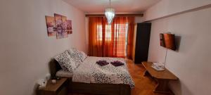 a bedroom with a bed and a table and a window at Central Residence in Ploieşti