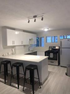 una cocina con encimera blanca y taburetes. en 8 Banyan Court, en Bridgetown
