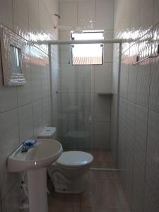 La salle de bains blanche est pourvue de toilettes et d'un lavabo. dans l'établissement Recanto Jubarte (Massaguaçu Caraguatatuba - SP), à Caraguatatuba