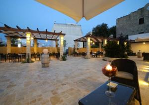 un patio con mesas, sillas y una sombrilla en Hotel Adriatico en Tricase