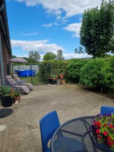 - une terrasse avec une table, des chaises et des fleurs dans l'établissement Vakantiewoning Schouwenberg, à Swalmen