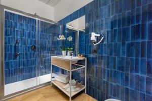 uma casa de banho em azulejos azuis com um lavatório e um chuveiro em Dreamers' Rooms Sorrento em Sorrento