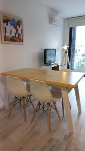 a wooden dining table with two white chairs around it at Delta Apart in Tigre