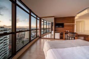 sypialnia z łóżkiem i dużymi oknami w obiekcie Hotel Laghetto Bento w mieście Bento Gonçalves