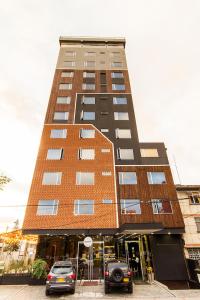 un edificio alto con coches estacionados frente a él en Hotel American Visa Tower, en Bogotá