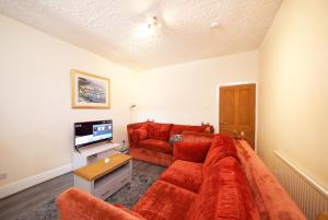 a living room with a red couch and a television at Crystal House 10min to Manchester City Centre ideal for work and leisure in Manchester