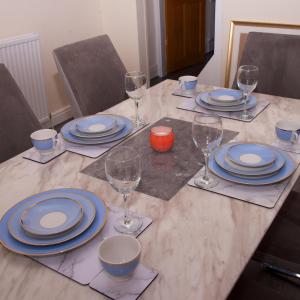 a table with blue and white plates and wine glasses at Crystal House 10min to Manchester City Centre ideal for work and leisure in Manchester