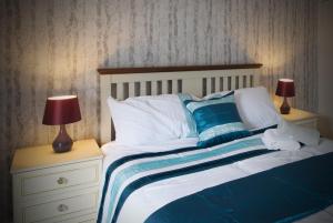 1 cama con almohadas azules y blancas y 2 lámparas en Crystal House 10min to Manchester City Centre ideal for work and leisure en Mánchester