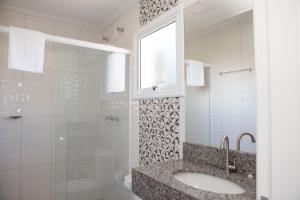 a bathroom with a sink and a glass shower at Pousada Bel Vedere in Vespasiano Corrêa