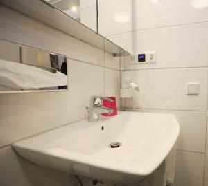 uma casa de banho com um lavatório branco e um espelho. em Tonis Apartment Erkrath em Erkrath