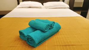 a green towel is sitting on a bed at SW Home MU **** Mont Choisy in Grand-Baie