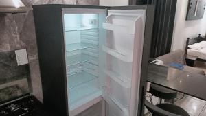 Un refrigerador vacío con la puerta abierta en una cocina. en SW Home MU **** Mont Choisy, en Grand Baie