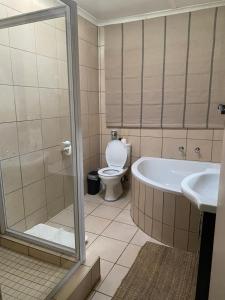 a bathroom with a tub and a toilet and a sink at Cabbage Tree Cottage in Hilton