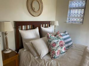 1 dormitorio con cama con almohadas y espejo en Cabbage Tree Cottage en Hilton