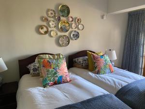 two beds in a room with plates on the wall at Cabbage Tree Cottage in Hilton