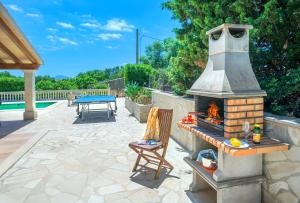 un patio con una chimenea de ladrillo con una mesa y una silla en Owl Booking Villa Payeras - 15 Min Walk to the Beach, en Puerto Pollensa