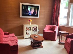 Rocky River Inn في New Milford: غرفة معيشة مع كراسي حمراء وتلفزيون