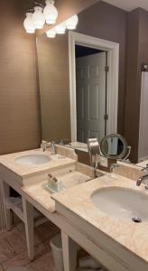 La salle de bains est pourvue de 2 lavabos et d'un grand miroir. dans l'établissement Rocky River Inn, à New Milford