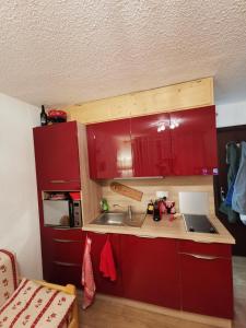una pequeña cocina con armarios rojos y fregadero en Studio les fleury, en Mieussy
