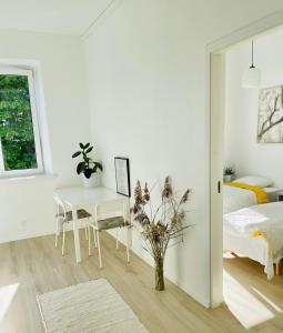 a white bedroom with a bed and a table at Endla Hostel ja Apartamendid in Haapsalu