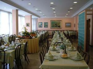 uma sala de jantar com mesas longas e cadeiras em Hotel Acerboli em Rimini