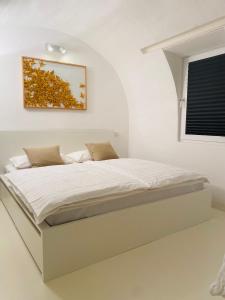 een bed in een witte kamer met een foto aan de muur bij FeWo Silberberg im Loftstil mit Terrasse in Leonberg