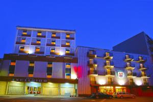 dwa wysokie budynki obok siebie w nocy w obiekcie Hotel Excelsior w mieście Monfalcone