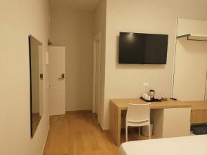 um quarto com uma secretária e uma televisão na parede em Nike Luxury Rooms em Agrigento