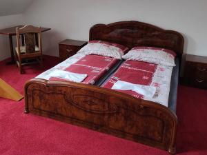 una cama de madera con 2 almohadas rojas y blancas. en Penzion Xaver, en Blučina