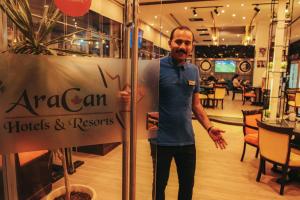 a man standing next to a sign in a restaurant at Aracan Portsaid in Port Said