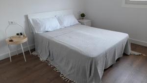 una camera da letto con un letto con un copriletto bianco e un tavolo di RAMALLOSA - SABARIS - BAIONA - NIGRAN - GONDOMAR a Pontevedra