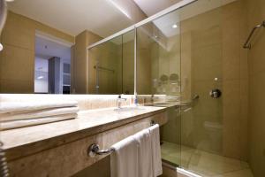 uma casa de banho com um chuveiro, um lavatório e um espelho. em Rio Hotel by Bourbon Ciudad Del Este em Ciudad del Este