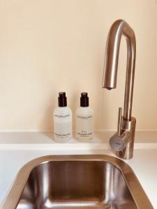 dos botellas de jabón sentadas en un fregadero en Casita aan Zee 2 slaapkamers 2 badkamers 3 min van zee, en Zandvoort