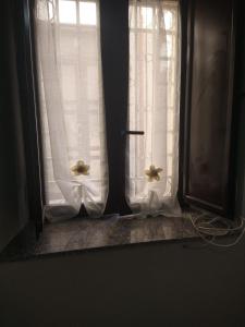 a window with white curtains with two gold clippers at Casa Cecilia in Gallico Marina +26 photos