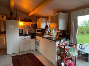 a kitchen with white appliances and a large window at Norsk bjælkehytte med fibernet in Slagelse